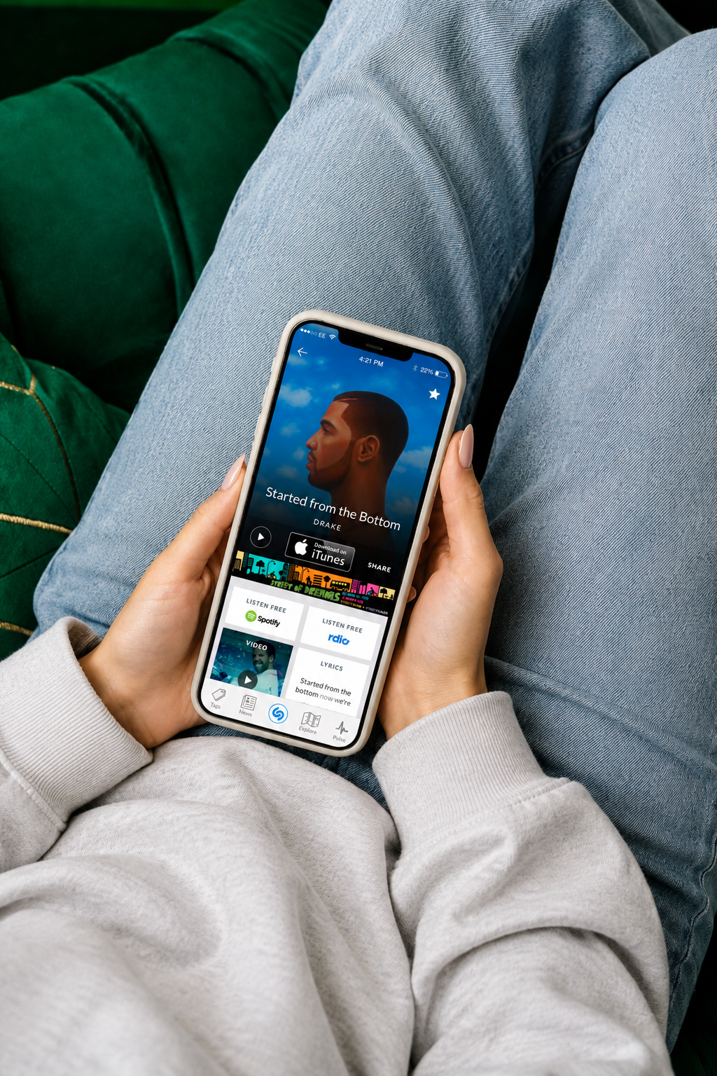 The Shazam discovery screen in a person's hands, showing artist video, lyrics, and listening services
